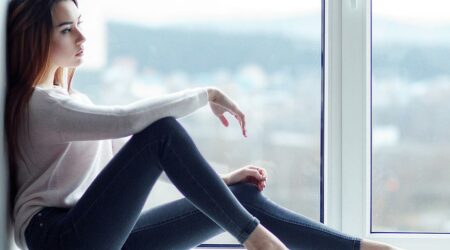 Eine Frau sitzt vor einem Fenster welches mit durchsichtiger Fensterfolie beklebt ist
