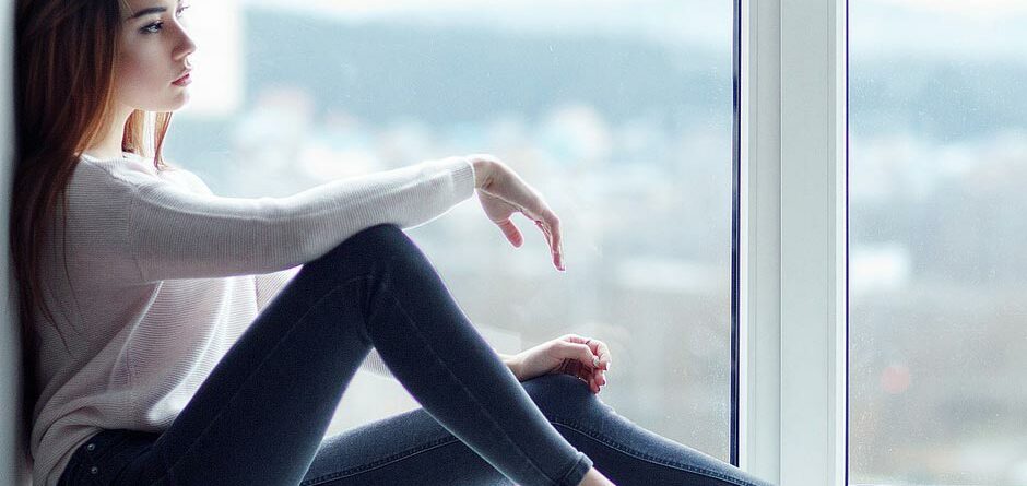 Eine Frau sitzt vor einem Fenster welches mit durchsichtiger Fensterfolie beklebt ist