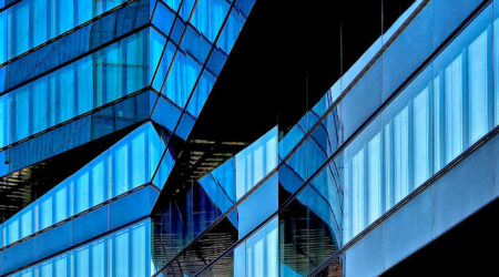 Zeigt eine Bürogebäude mit vielen Fenster und angebrachter blau grauer Sonnenschutzfolie