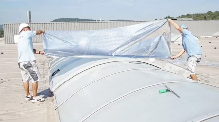 Ein Montageteam verklebt Sonnenschutzfolie auf Polycarbonatstegplatten